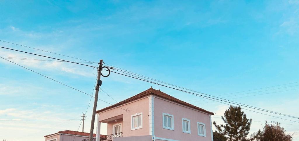 ein rosafarbenes Gebäude mit einer Stange und einem blauen Himmel in der Unterkunft Mãe Home Story in Caldas da Rainha