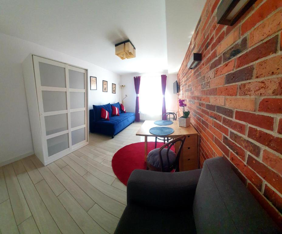 a living room with a brick wall and a blue couch at Apartamenty Orchidea Łeba in Łeba