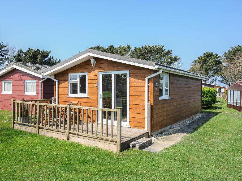 een tiny house met een veranda en een hond op de veranda bij Little Trebah in Saint Merryn