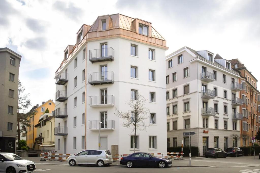 Biały budynek z samochodami zaparkowanymi przed nim w obiekcie Nest - Kanzleistrasse 217 w Zurychu