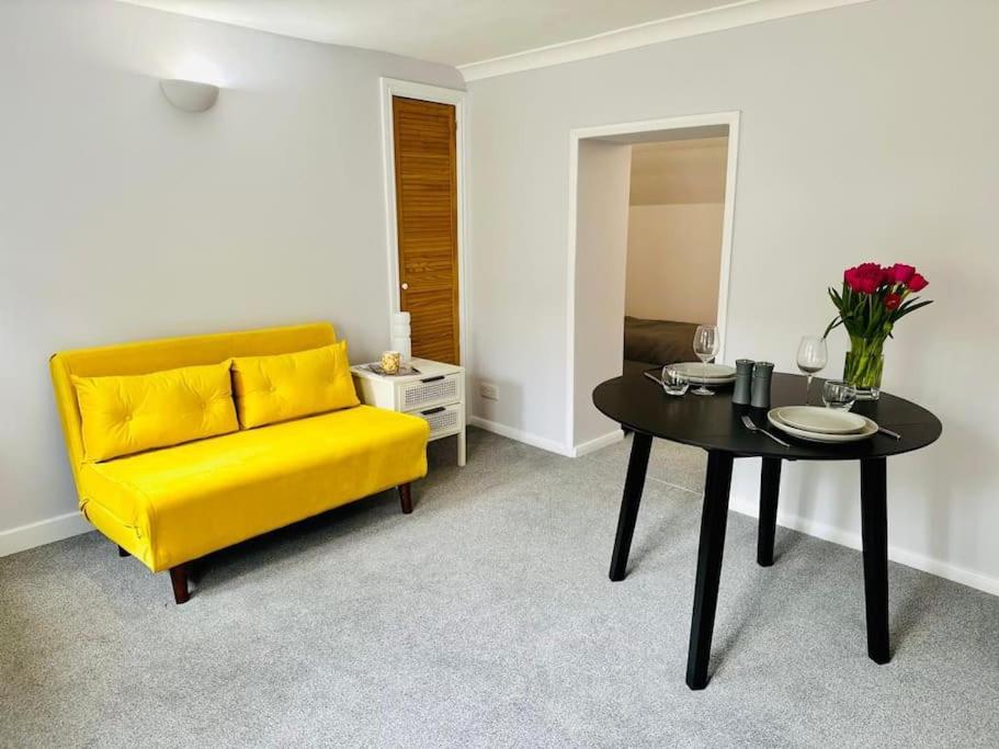 um sofá amarelo e uma mesa num quarto em Flat in Cheltenham em Cheltenham