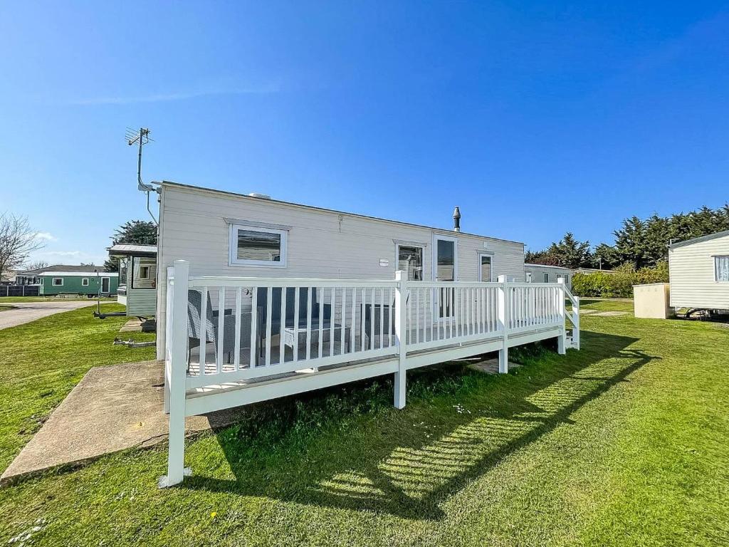 a white mobile home with a white fence at Gorgeous Caravan With Decking In Breydon Water Holiday Park, Ref 10081b in Belton