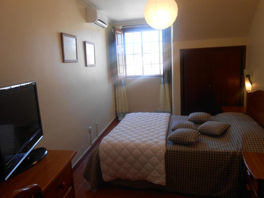 a bedroom with a bed with pillows and a television at Apartamentos Turisticos Queluz in Queluz