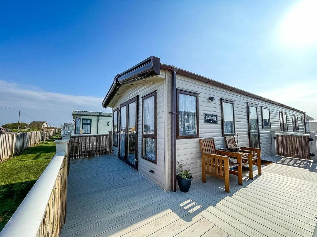 a tiny house on a deck with a table and chairs at Beautiful Caravan With Sea Views At California Cliffs In Scratby Ref 50010oc in Great Yarmouth