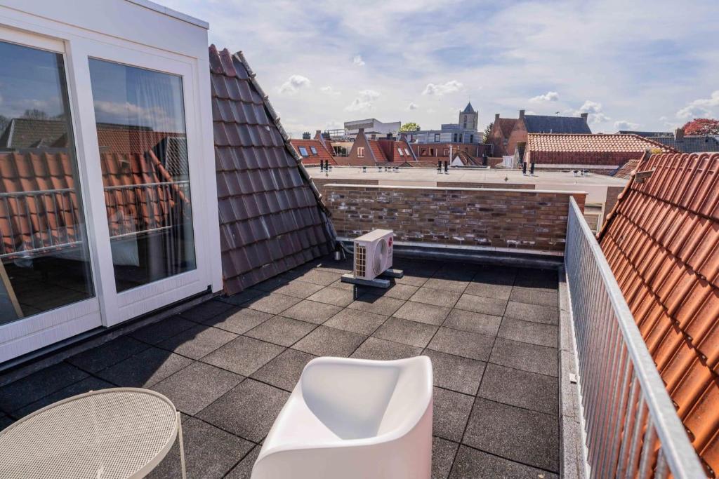 a balcony with a white chair on a roof at Exclusive 70m2 One-Bedroom Apartment in Tiel