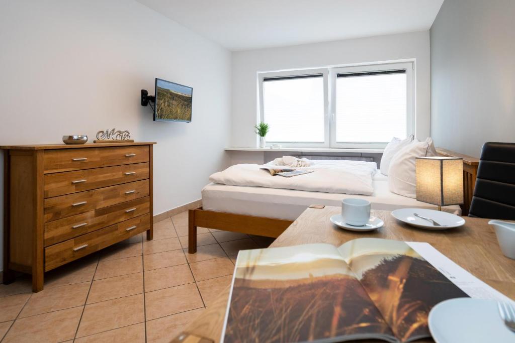 ein Schlafzimmer mit einem Bett und einem Tisch mit einem Buch in der Unterkunft Adrian 5 in Westerland