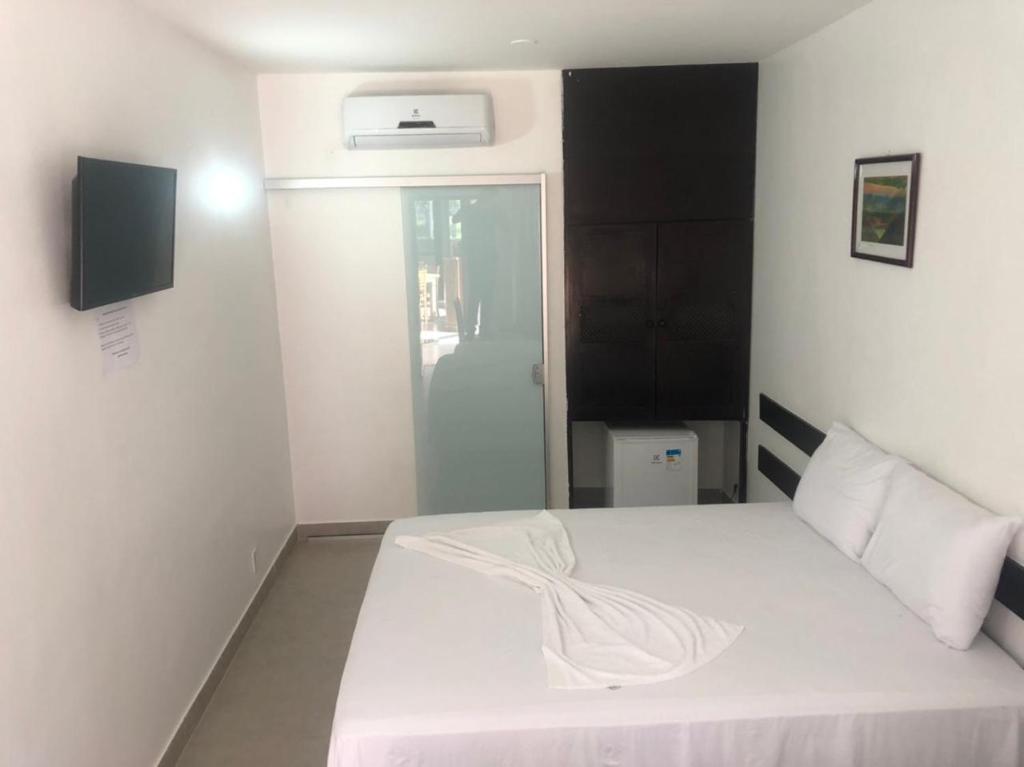 a bedroom with a white bed with a white blanket at Hotel Porto Brasília in Porto Seguro