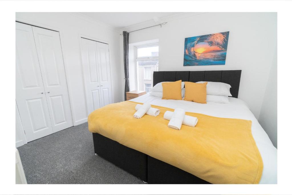 a bedroom with a large bed with two towels on it at Business friendly 3BR home - King size beds & Centrally located in Swansea
