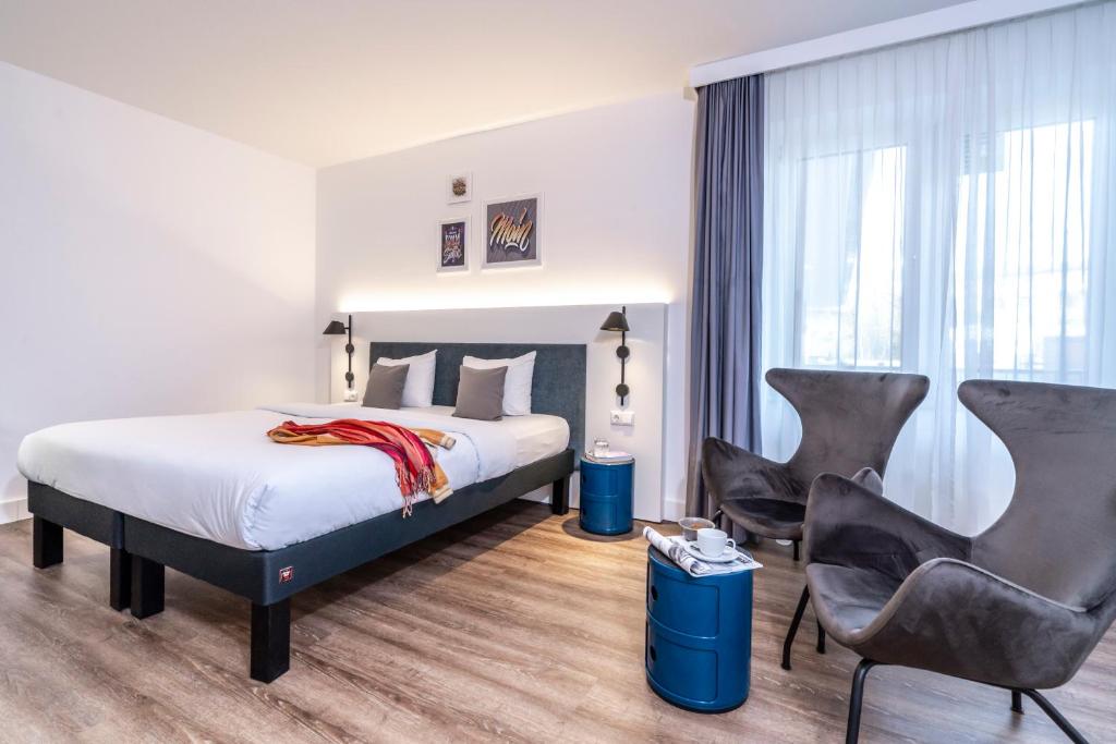 a hotel room with a bed and two chairs at ibis Styles Hamburg Alster City in Hamburg