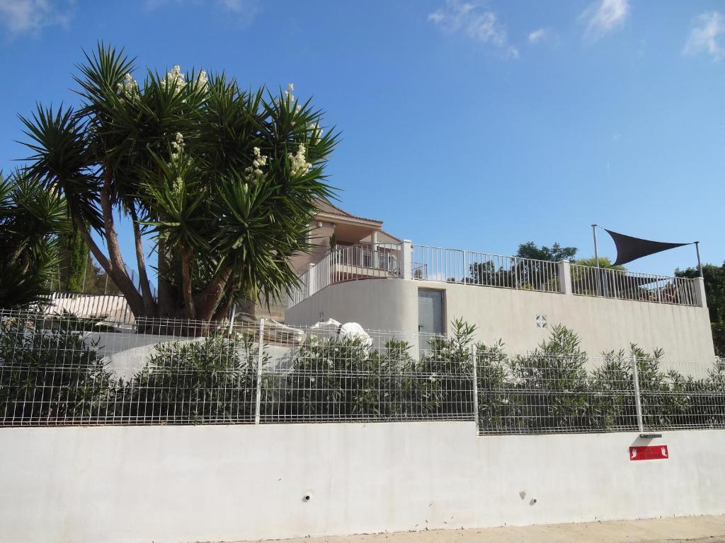 ein weißes Gebäude mit einem Zaun und Palmen in der Unterkunft LAS PALOMAS, appartement 3 chambres avec piscine in Turís
