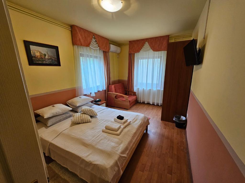 a bedroom with a bed and a chair and windows at Abigél 2 Vendégház in Miskolctapolca