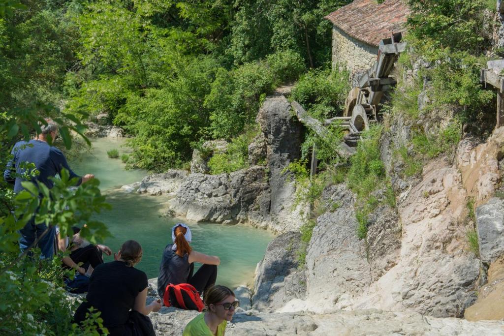 een groep mensen die aan de kant van een rivier zitten bij Traditional Stone House Kotli in Buzet