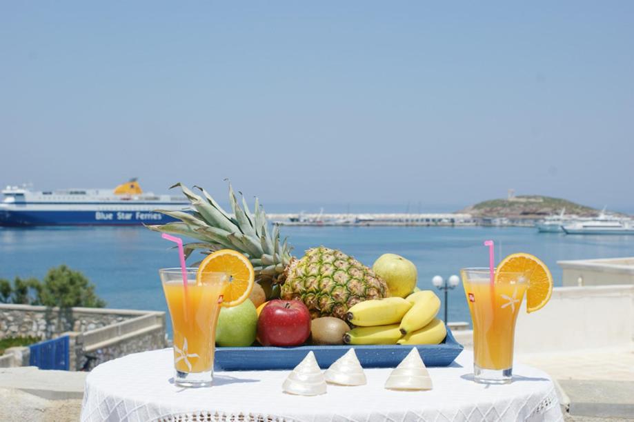 una bandeja de fruta en una mesa con dos vasos de zumo en Athina Apartments Naxos Town, en Naxos Chora