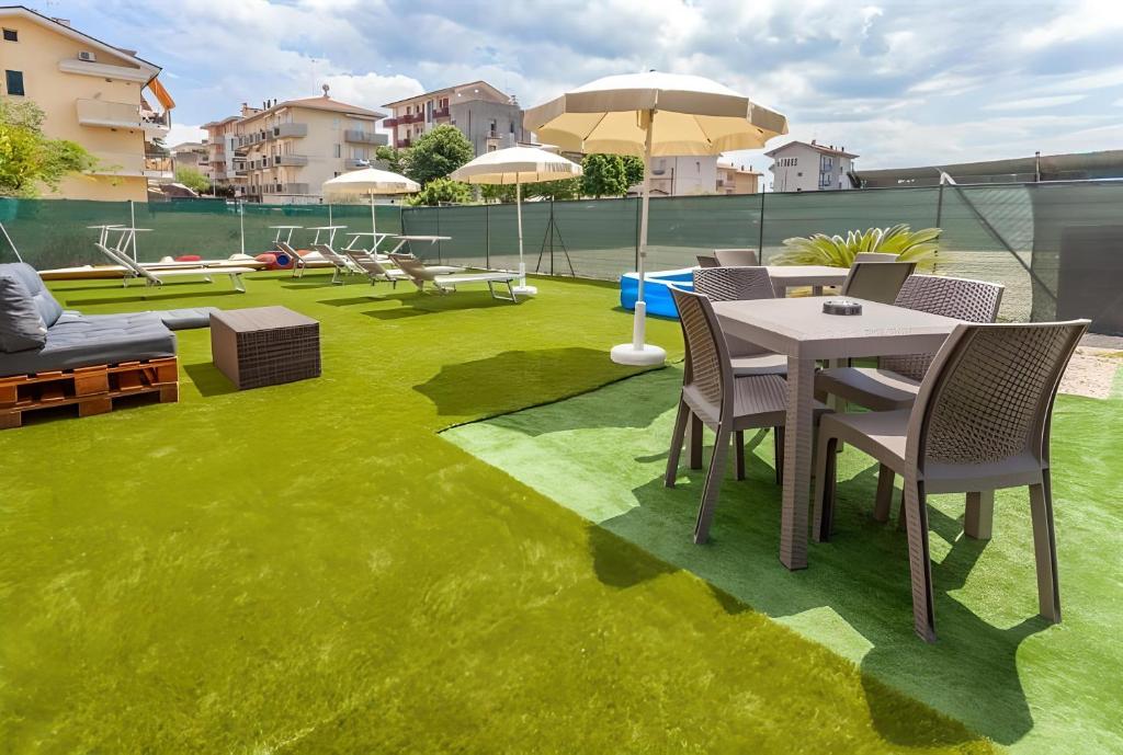 eine Terrasse mit grünem Gras sowie einem Tisch und Stühlen in der Unterkunft Sole in Rimini