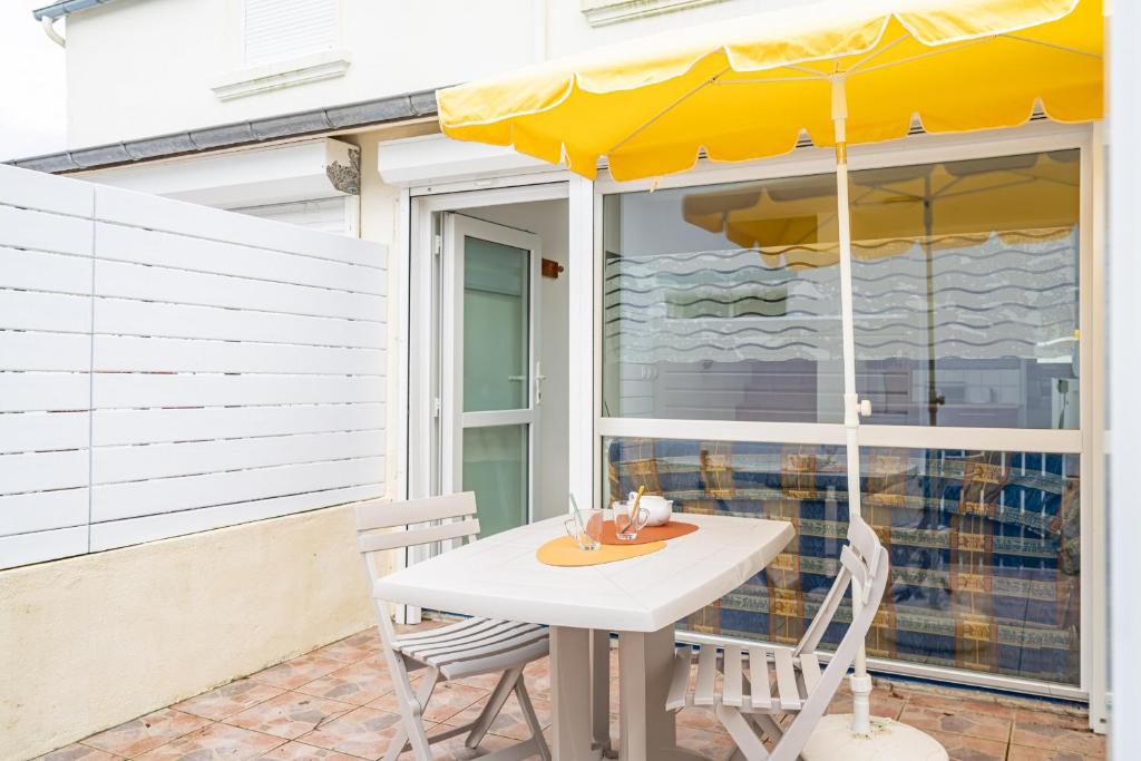 een tafel en stoelen met een parasol op een patio bij Vacances en duo au Guilvinec ! in Le Guilvinec