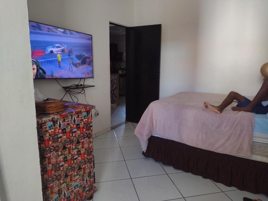 una persona sentada en una cama viendo una tele en casatemporada05, en Cabo Frío