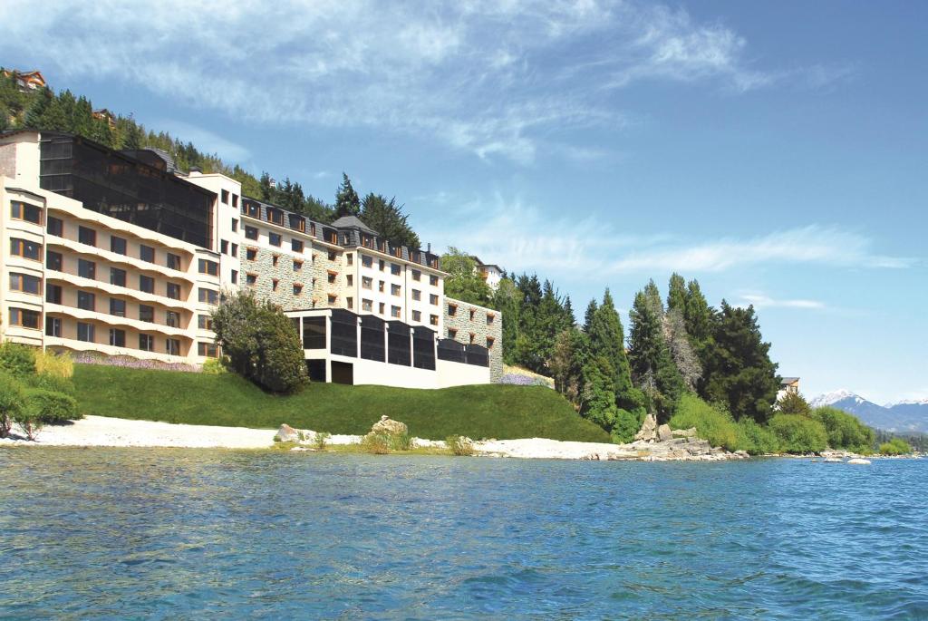 a large building sitting on top of a lush green hillside at Alma Del Lago Suites & Spa in San Carlos de Bariloche