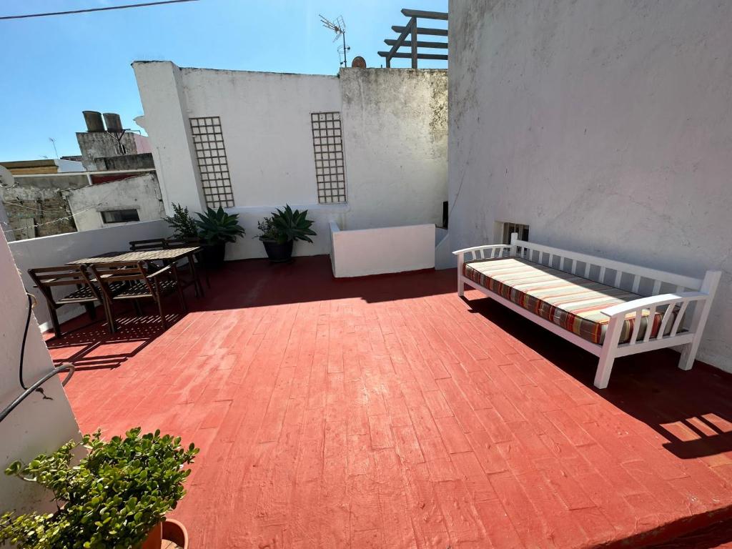 uma varanda com uma cama e uma mesa num edifício em Apartment in old town with roof terrace and fibre, Tarifa em Tarifa