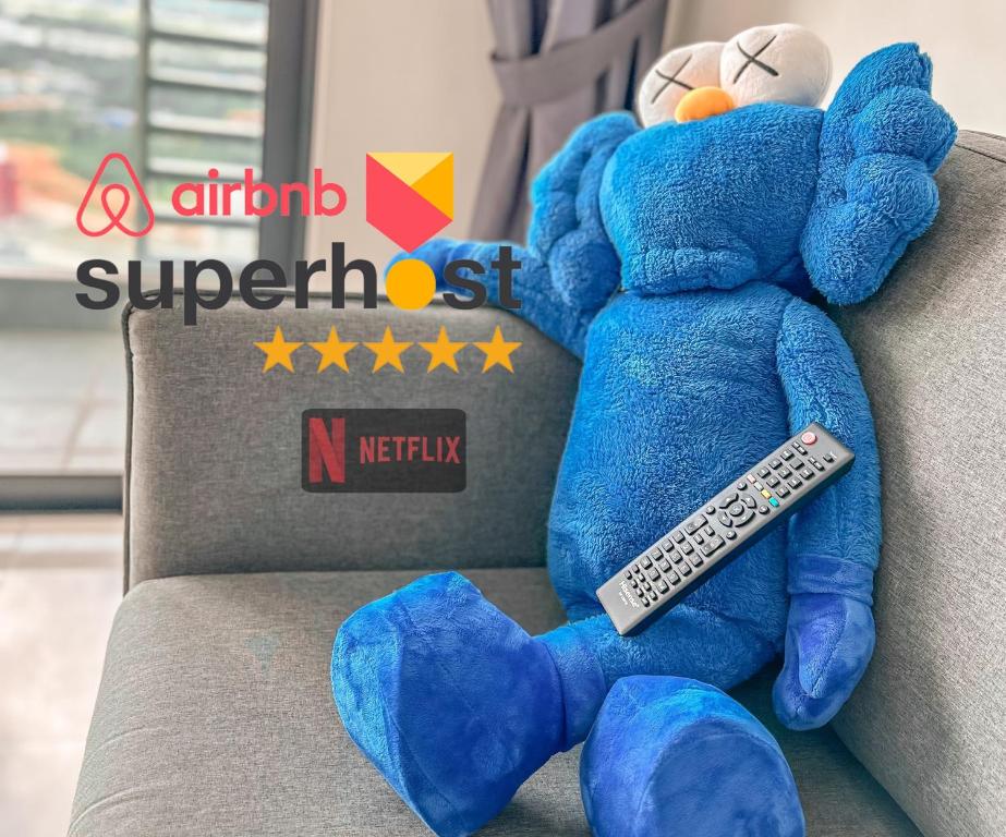 a blue teddy bear sitting on a couch with a remote control at StarryHomes 33 @ Green Haven 3Beds 2Bedsroom2Bath in Masai