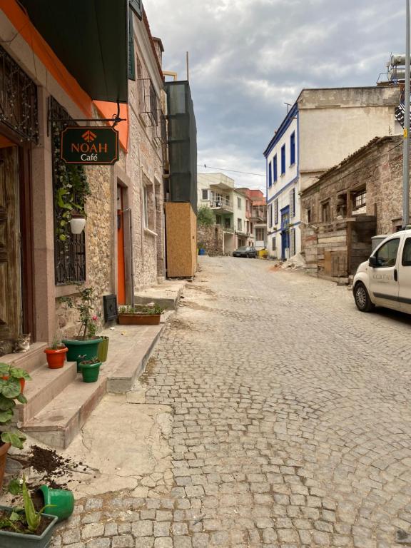 een geplaveide straat in een oude stad met een auto bij Ayvalık'taki Eviniz in Ayvalık