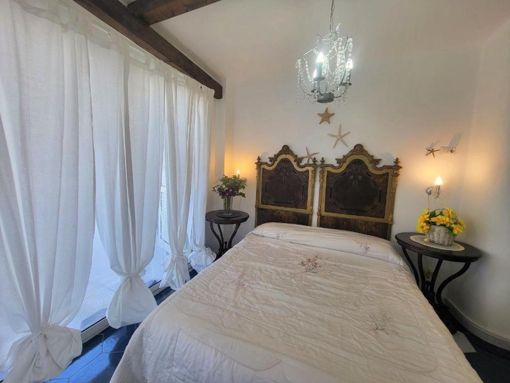 トロペアにあるCasa Vacanze Miceliのベッドルーム1室(カーテンとシャンデリア付きの大型ベッド1台付)