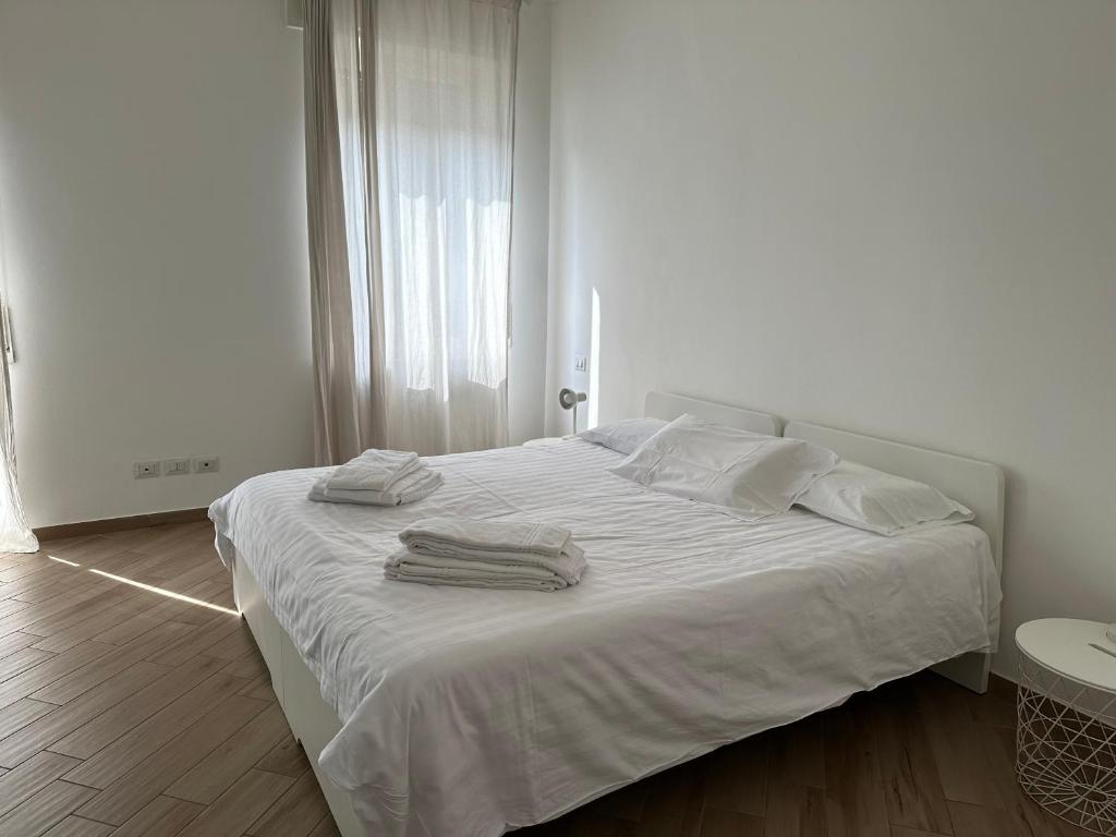 una camera bianca con un letto bianco e asciugamani di Appartamento via centro a Verona