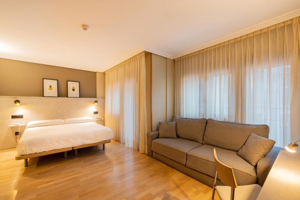 Hotel Santamaria في توذيلا: غرفه فندقيه بسرير واريكه