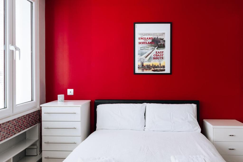1 dormitorio rojo con 1 cama y pared roja en Amazing Studio Flat in Central London. Stylish & Cosy, en Londres