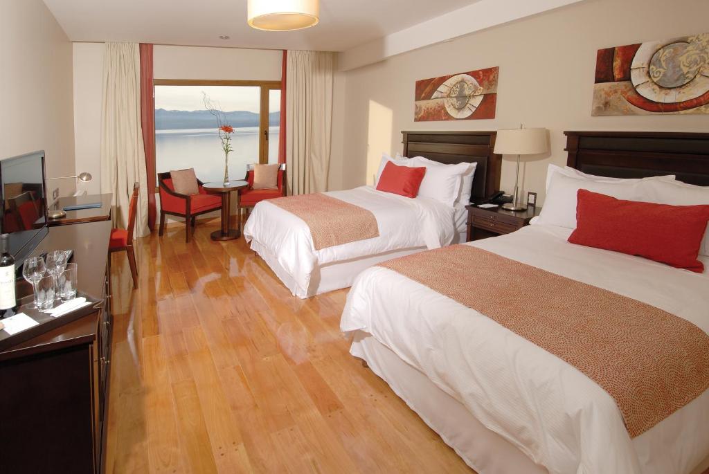 a hotel room with two beds and a television at Alma Del Lago Suites & Spa in San Carlos de Bariloche