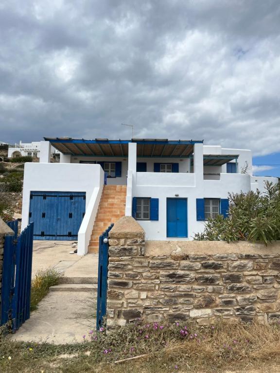 a white house with blue doors and a stone wall at Vintage lover's getaway in Andiparos