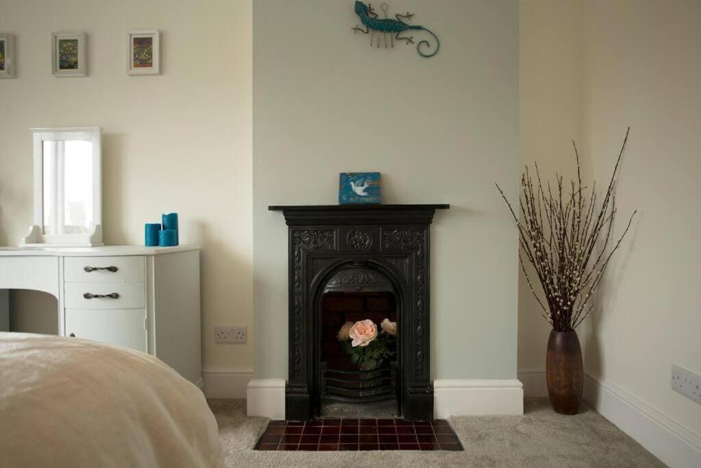 a room with a fireplace with a vase of flowers at Rie's Retreat - The Emerald room in Glastonbury