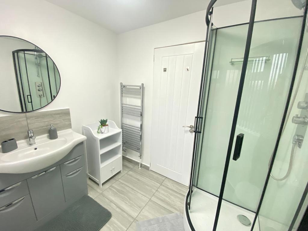 a white bathroom with a sink and a shower at Gatwick Deluxe En-suite Rooms in Horley