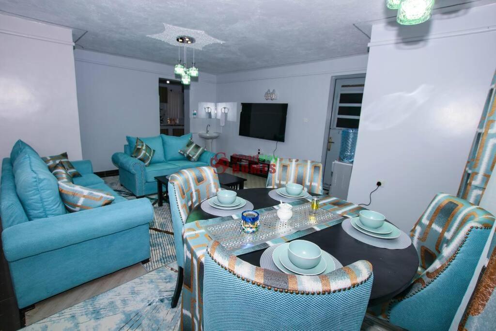 a living room with a table and a blue couch at Atlantic House 3 Bedroom, Naivasha in Naivasha