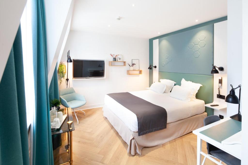 a hotel room with a bed and a tv at Hôtel Vendome Saint-Germain in Paris