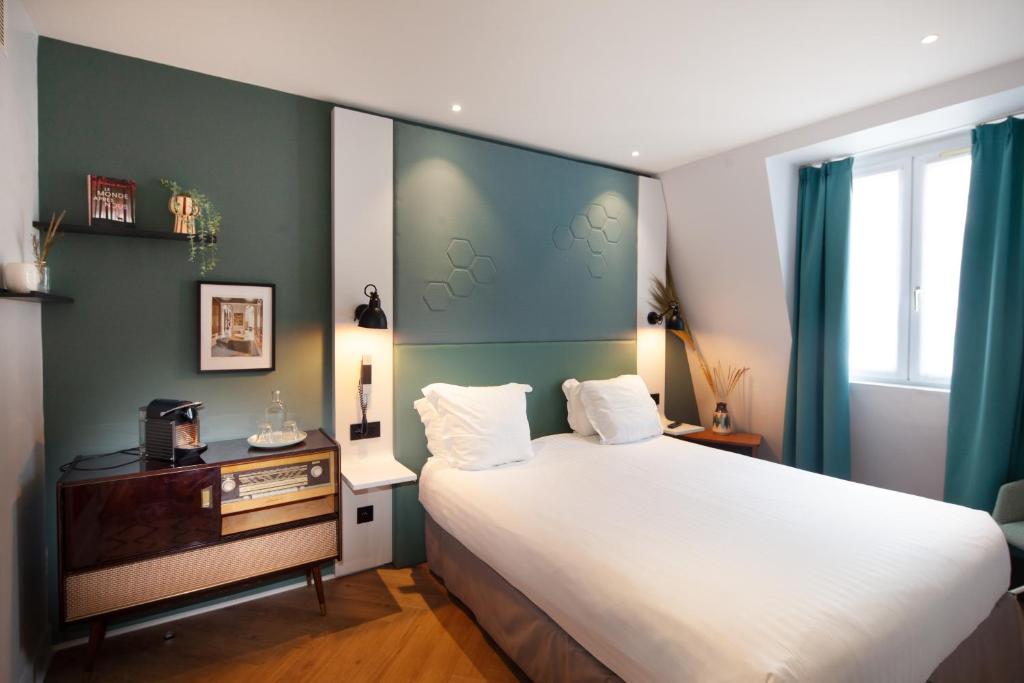 a bedroom with a large white bed and a desk at Hôtel Vendome Saint-Germain in Paris
