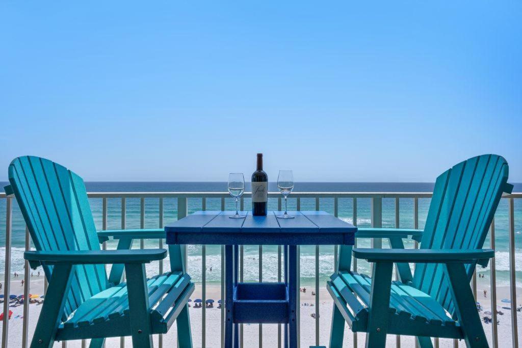 a table with a bottle of wine and two chairs on the beach at Majestic Sun 806B in Destin