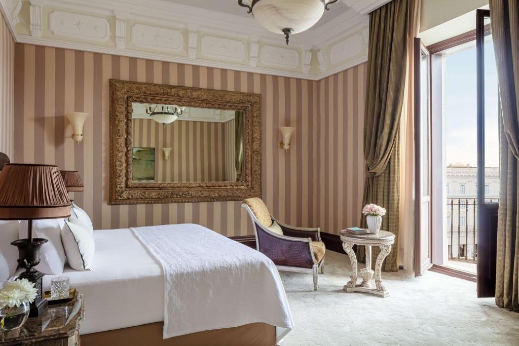 una camera con letto, specchio e sedia di Anantara Palazzo Naiadi Rome Hotel - A Leading Hotel of the World a Roma