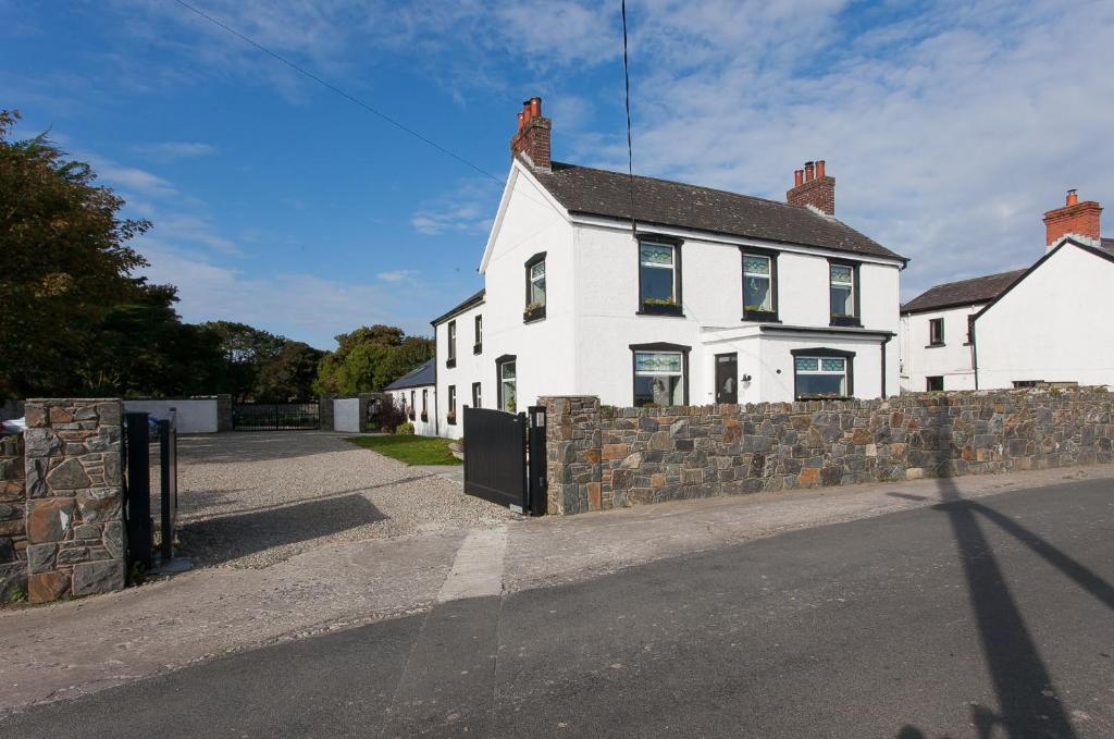 a white house on the side of a street at Manse On The Beach in Kirkistown