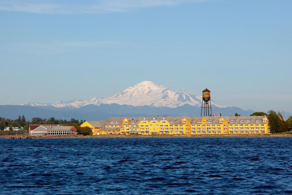 Semiahmoo Resort and Spa في بلين: مبنى أصفر كبير مع جبل مغطى بالثلج في الخلفية