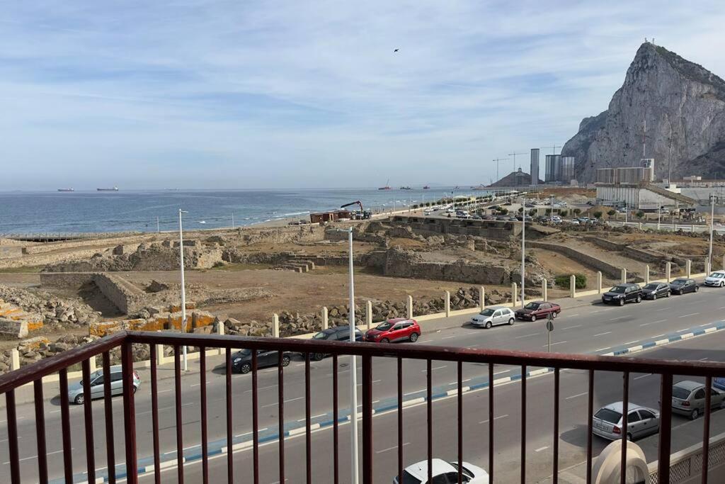 una carretera con coches aparcados en ella junto al océano en Primera línea de playa y Gibraltar a 5 minutos, en La Línea de la Concepción
