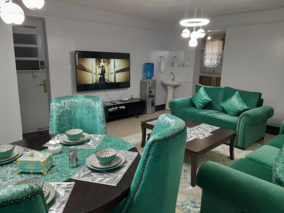 a living room with green chairs and a table at Gamtoos House:Lovely 3 Bedroom House in Naivasha