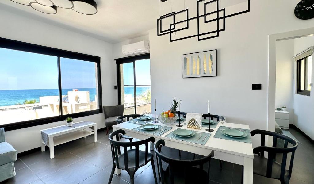 a dining room with a table and chairs and the ocean at GW945 Gugel Waves Amazing Seaview Apartments in Nahariyya