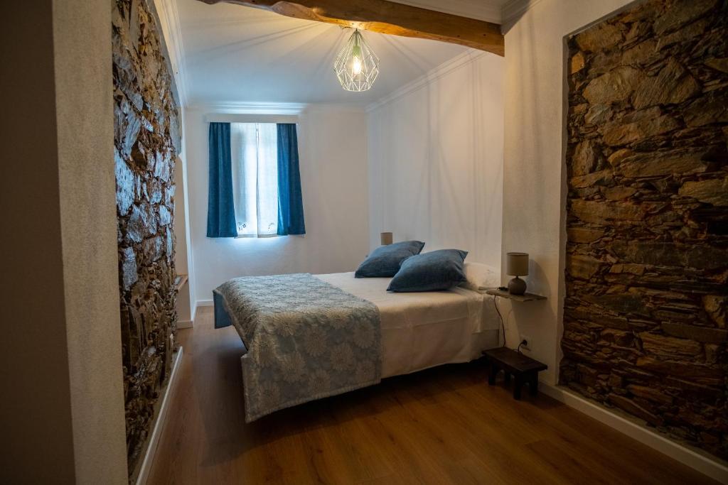 a bedroom with a bed with blue pillows and a window at Casa das Ruas (Xisto Sentido®) 