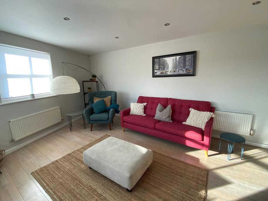 a living room with a red couch and two chairs at The Penthouse, Winchester in Winchester