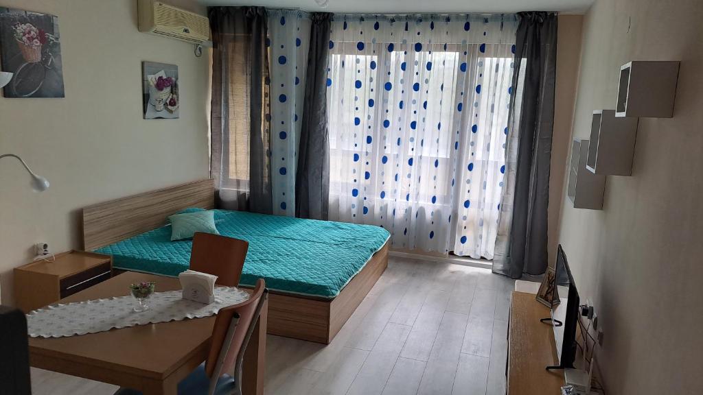 um pequeno quarto com uma cama, uma mesa e uma sala de jantar em Studio Demokratsia em Burgas