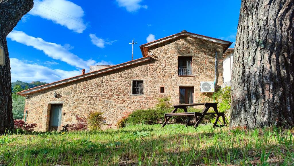 ein altes Steinhaus mit einem Picknicktisch neben einem Baum in der Unterkunft Il Fienile tra gli Ulivi in Lamporecchio
