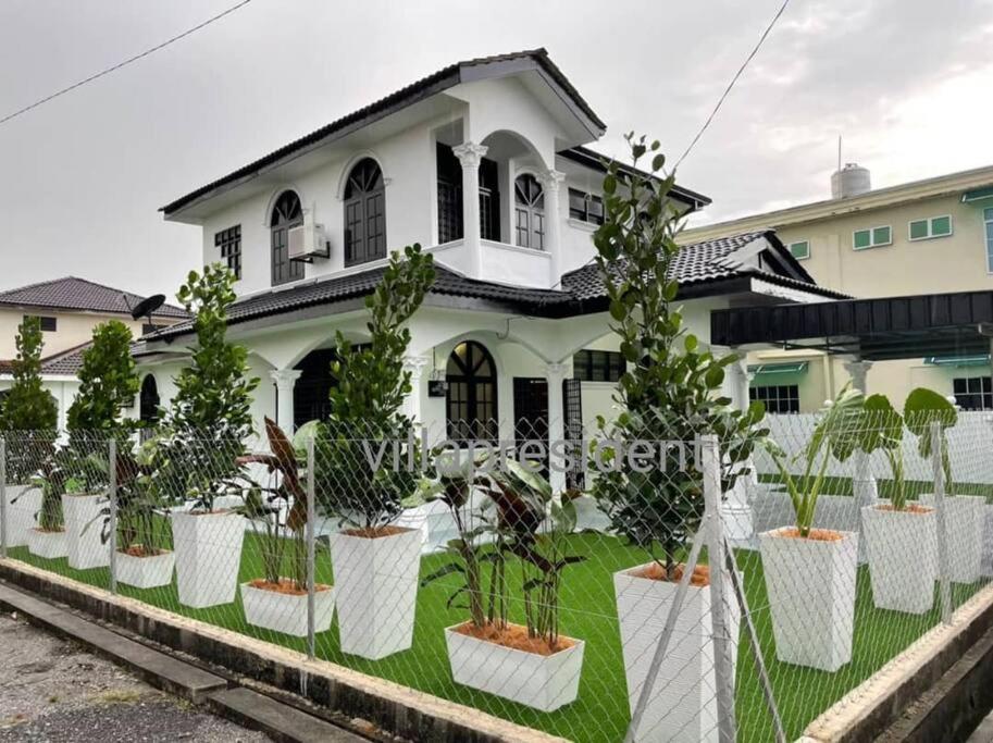 a white house with potted plants in front of it at Villa President Homestay -4 bedroom Aircond WIFI Vacations Home in Kampung Kerangi