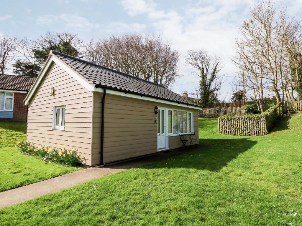a small shed in a yard with a grass field at 12 The Dell in Norwich