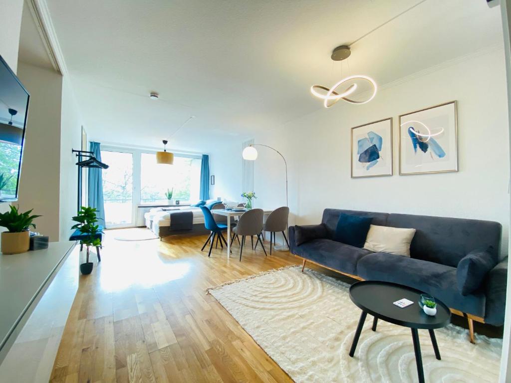 uma sala de estar com um sofá azul e uma mesa em KYANIT APARTMENT: FREE PARKING + POOL + NETFLIX em Wuppertal