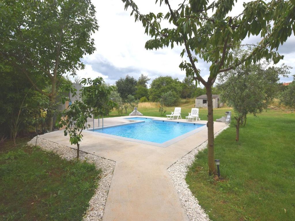 a swimming pool in a yard with two chairs next to it at Apartment in holiday home with private pool garden with grill airco and wifi in Banjole